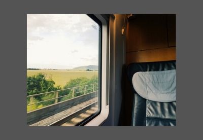Image shows a seat on a train carriage beside a window with English countryside passing outside