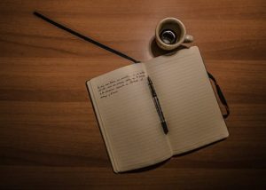 Open notebook with writing and a coffee cup