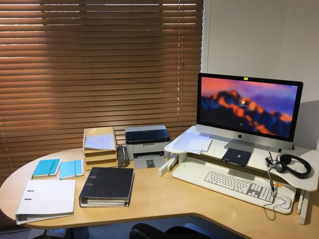 Image shows the layout of Rachel Amphlett's writing desk with lever arch files, notebooks, a printer and an iMac