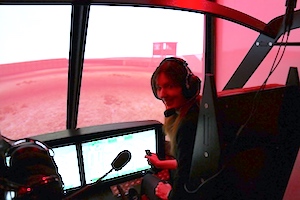 Image shows Rachel Amphlett wearing a headset in the pilot's seat of a Black Hawk helicopter simulator