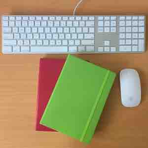 Notebooks and Apple keyboard on desk
