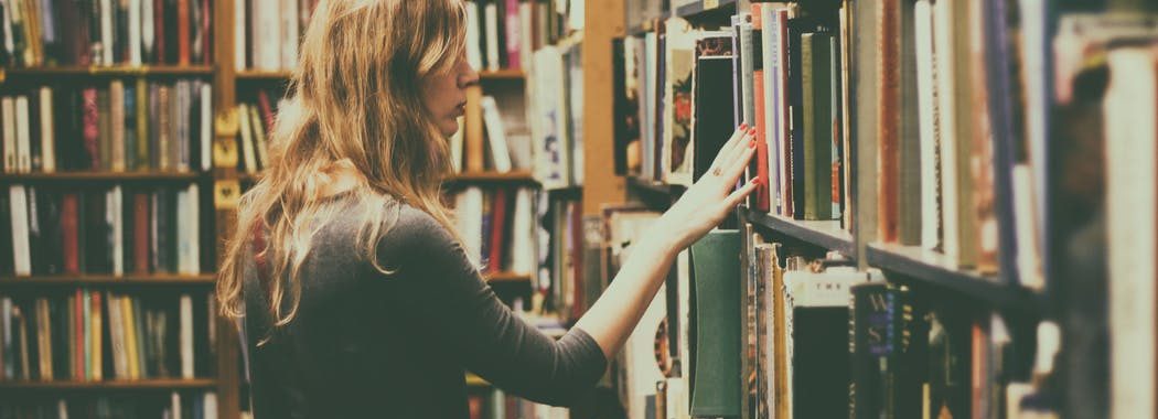 Image shows woman browsing library shelf