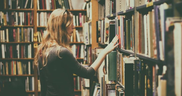 Image shows woman browsing library shelf