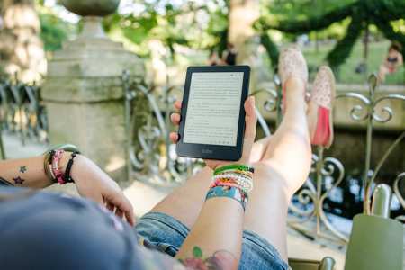 Image shows a woman reading a Kobo eReader on holiday 450x300