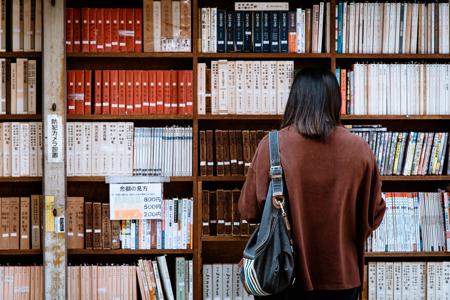 Woman with her back to the camera browsing library shelves
